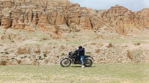 Man on motorbike admiring rugged cliffs in Mustang, Nepal